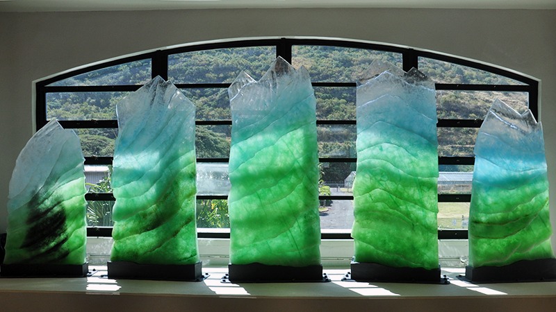 Photograph of the sculpture "Spirit of Manoa" - 5 cast-glass structures in front of a window