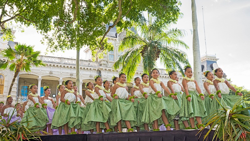 Group of young hula dancers walking onto a stage.
