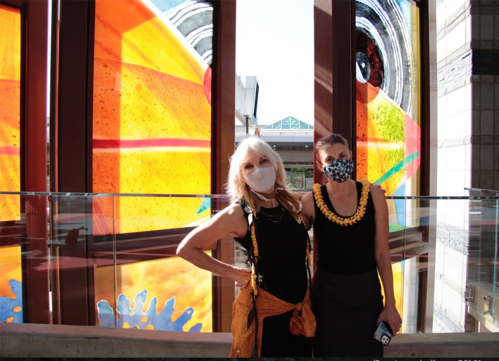 Two people standing in front of a glass artwork.