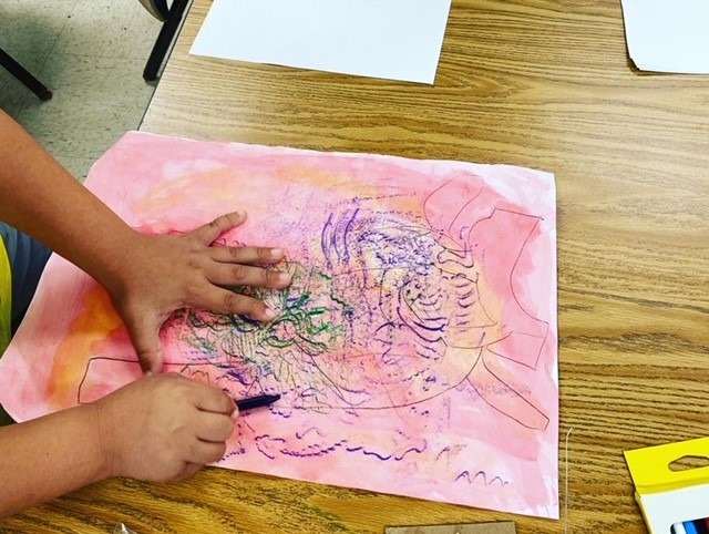 Child's hands holding a drawing tool and a painting.