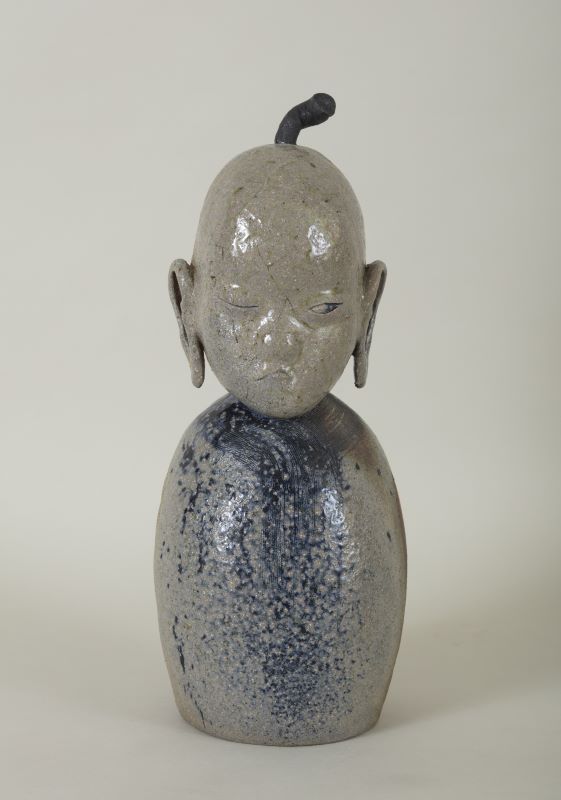 Ceramic figure with a humanoid head and rounded body with no limbs.
