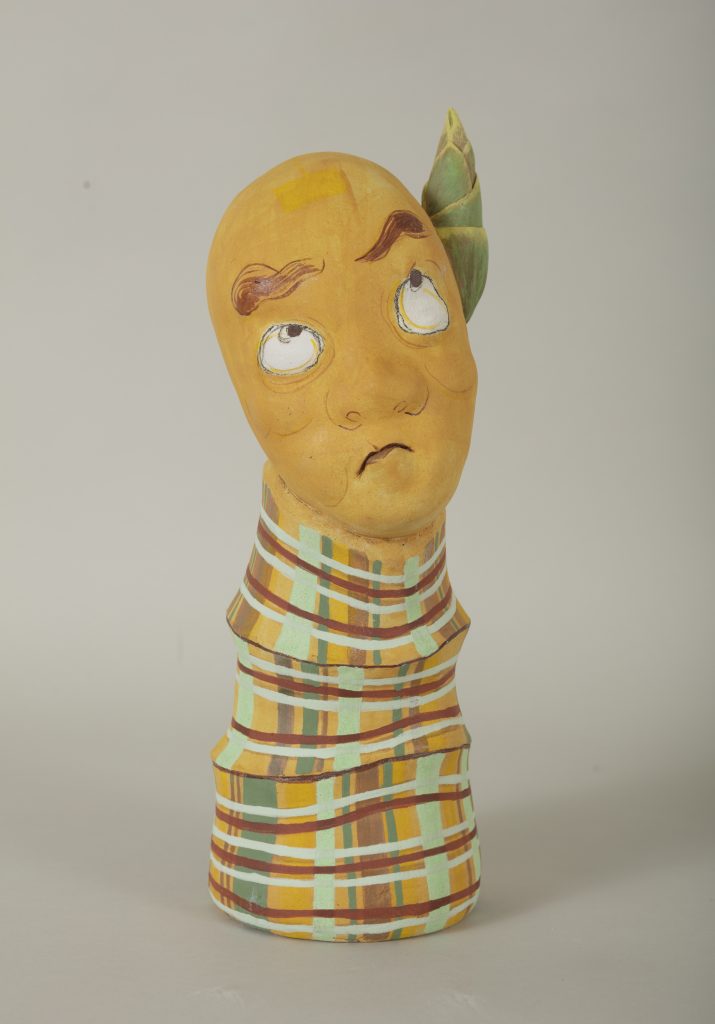 Ceramic figure with a humanoid head and bamboo stalk shaped with no limbs. A bamboo shoot emerges from the left side of the head.