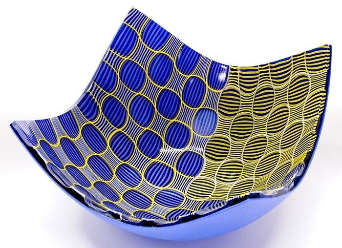 View looking down into a shallow glass bowl made from a flat square of glass in shades of blue, yellow, and black.