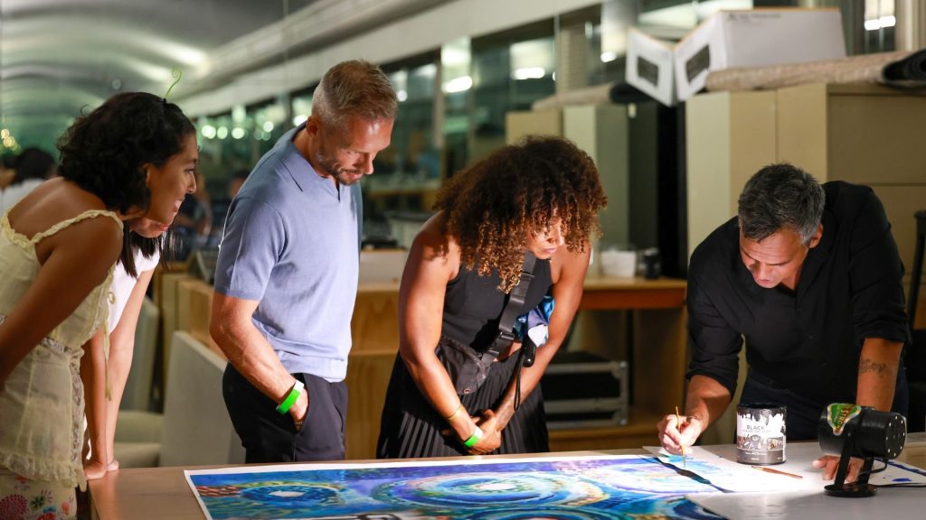 Group of people leaning over a painting