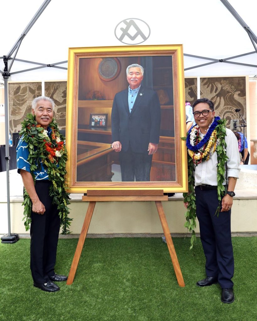 Painting of Governor David Ige. Governor Ige is standing on the left side of the photo. Artist Kirk Kurokawa is standing on the right side of the photo.