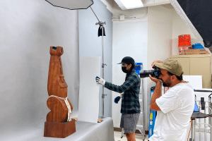Carved wood sculpture being photographed.