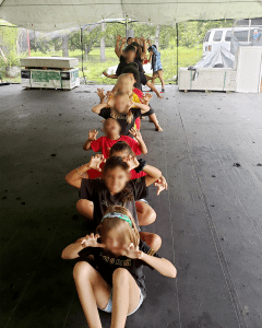 Students lined up in a long row, making different shapes with their arms and hands.